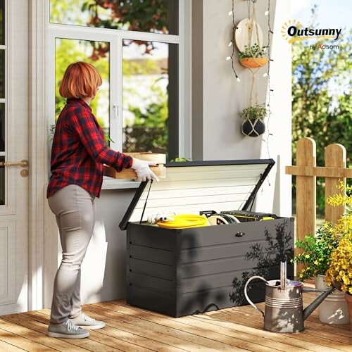 Person organizing items in outdoor storage bench on patio.